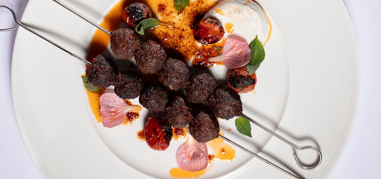 Perse Koobideh, garnished with special sauce and tomatoes